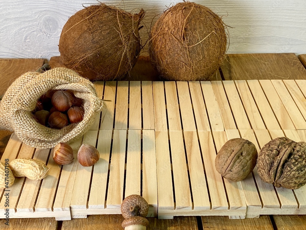 On the oak table are coconut, walnuts and hazelnuts - obrazy, fototapety, plakaty 