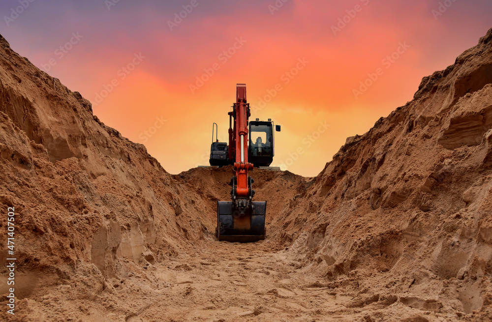 Excavator dig trench on sunset background. Backgoe on earthwork. Construction natural gas pipeline. Construction the sewage and drainage.  Laying sewer pipes at construction site. Open pit mining. - obrazy, fototapety, plakaty 