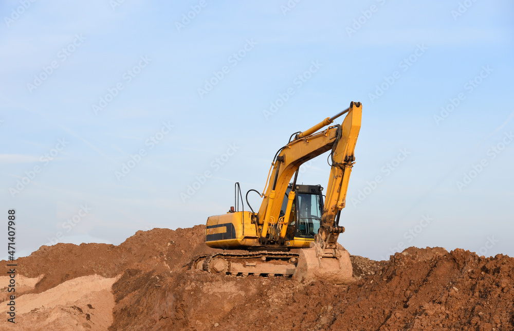 Excavator digs ground at construction site. Backgoe on earthwork. Construction foundation pit and road works. Development of a quarry for the extraction of sand and minerals. Open pit mining.
