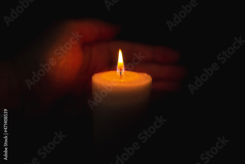 One palm take care of candle fire at night.Selective focus,Dark black background.Closeup.