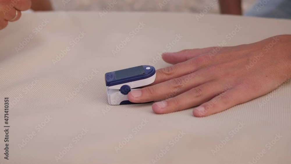 A close-up of a woman measures the pulse and oxygen of a patient using a pulse oximeter. A close-up of a woman measures the pulse and oxygen of a patient using a pulse oximeter.