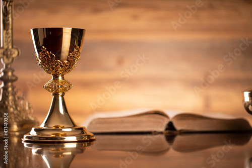 Catholic symbols composition. Religion concept. Holy Bible, rosary and golden chalice on the brown background. 