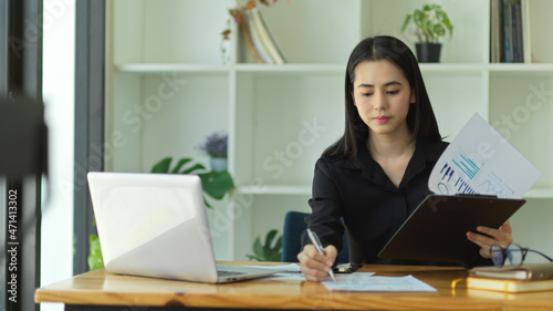 Financial woman working with laptop and financial report at her office desk. © bongkarn