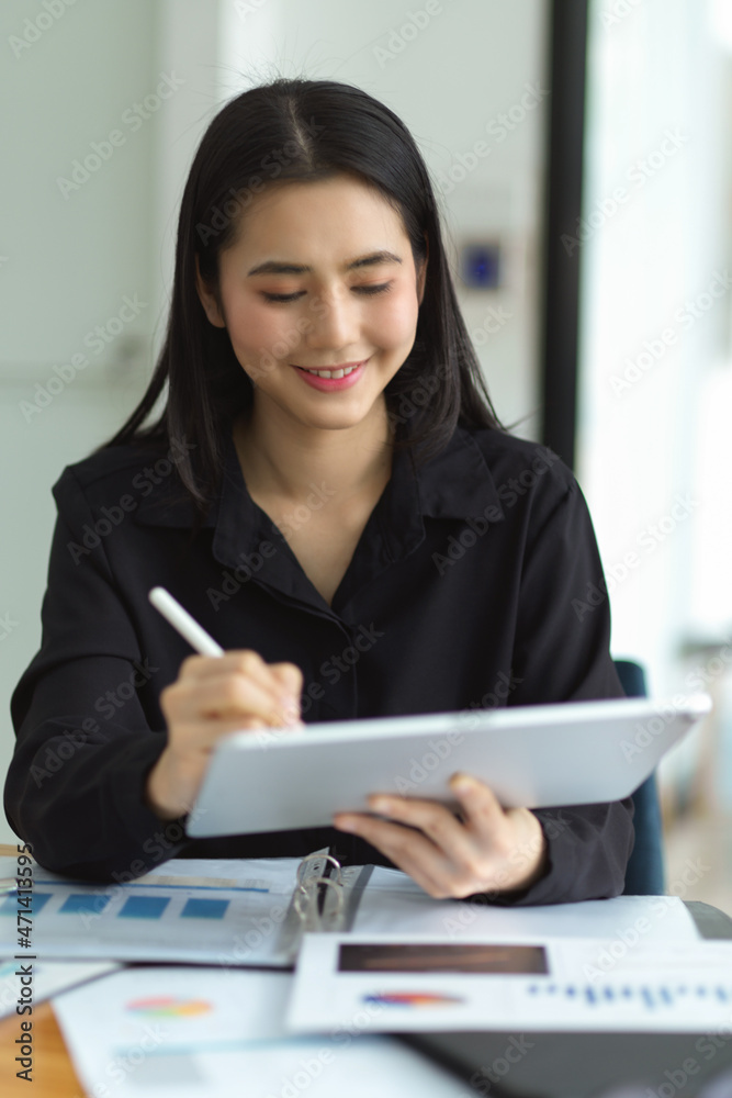Cheerful asian female employee working with digital tablet