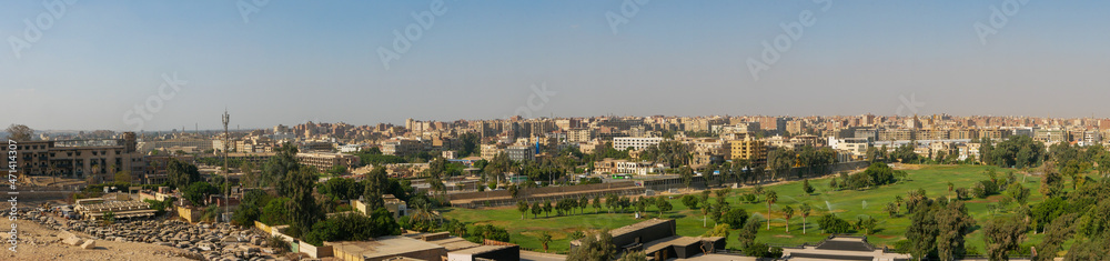 Giza, Cairo, Egypt - September 30, 2021: Panoramic view of the city of Cairo. Park with a green lawn and tall palm trees against the backdrop of city buildings.