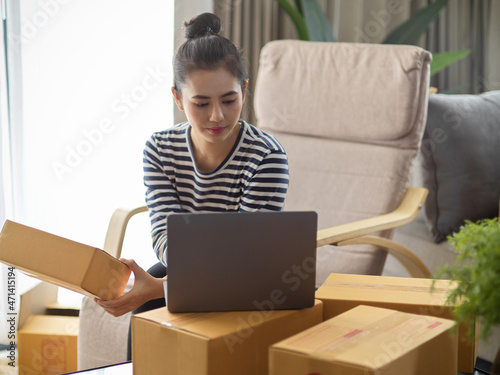 A successful SME business entrepreneur works on her laptop computer