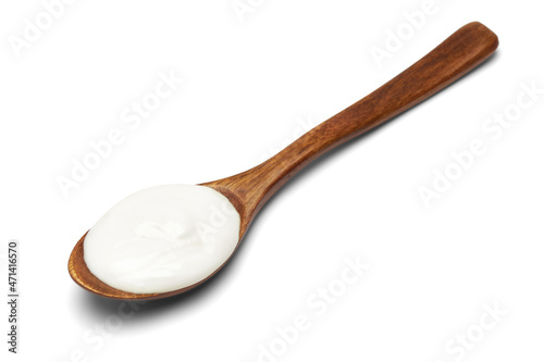 Sour cream in wooden spoon isolated on white background