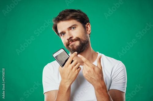 man in a t-shirt with a phone in his hand on a green background cropped view