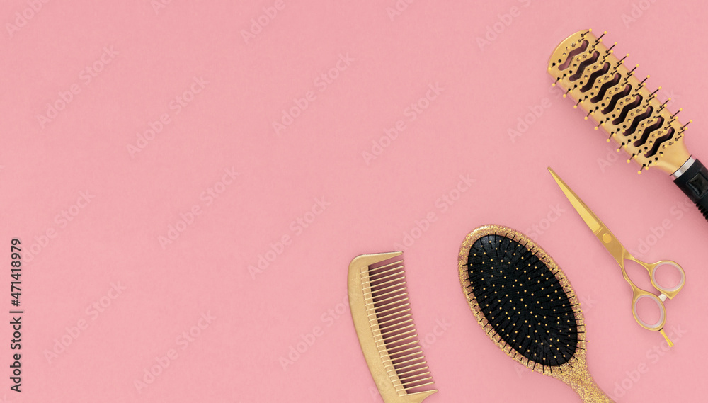 Golden hairdressing tools scissors combs on pink background