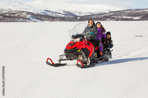 Mother with children on red snowmobile