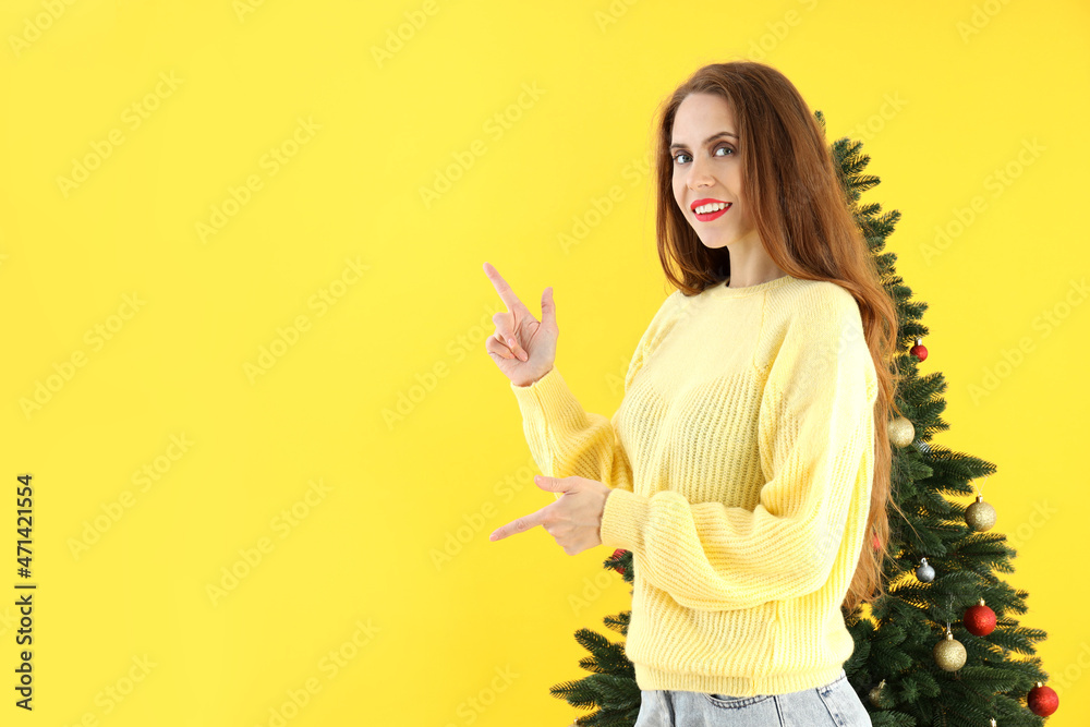 Attractive woman and Christmas tree on yellow background Attractive woman and Christmas tree on yellow background