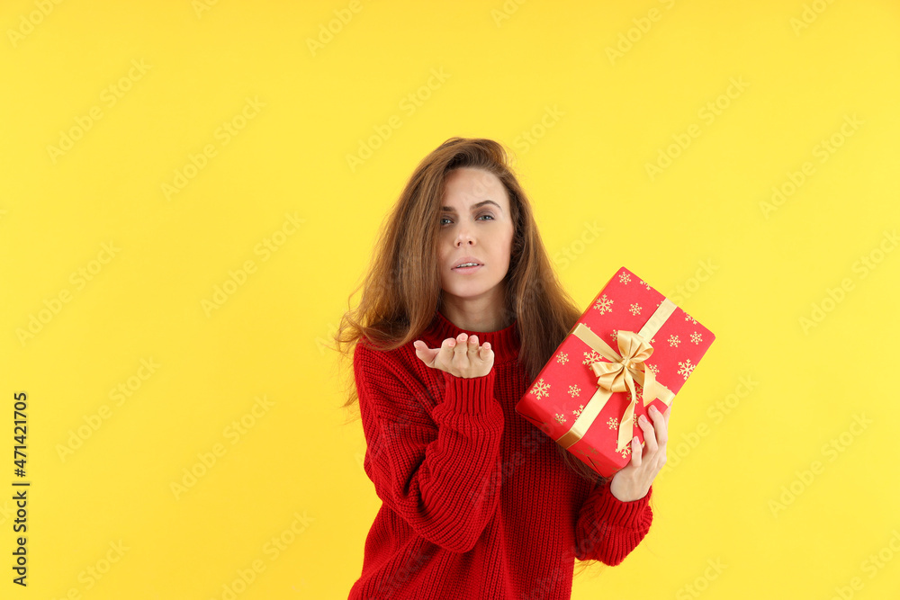 Attractive woman with Christmas gift box on yellow background Attractive woman with Christmas gift box on yellow background