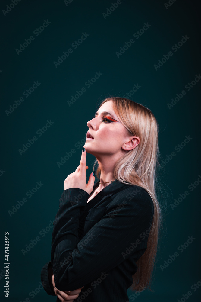 Young caucasian business woman wearing a black blazer in a photography studio with a blue dark background. Young caucasian business woman wearing a black blazer in a photography studio with a blue dark background.