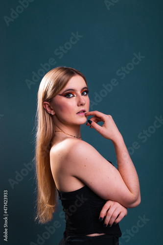 Young caucasian woman wearing all in black modeling in a photography studio with a blue dark background. © Jorge Argazkiak