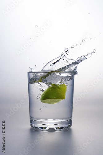 Lime clove splashing into a glass of water.