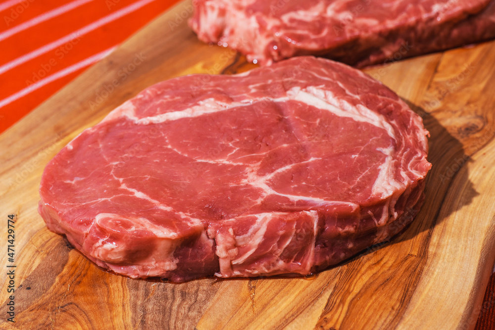 Two rib eye steaks on a wooden cutting board. Premium beef product. Fresh meat. Butcher craft and food supply industry. Two rib eye steaks on a wooden cutting board. Premium beef product. Fresh meat. Butcher craft and food supply industry.