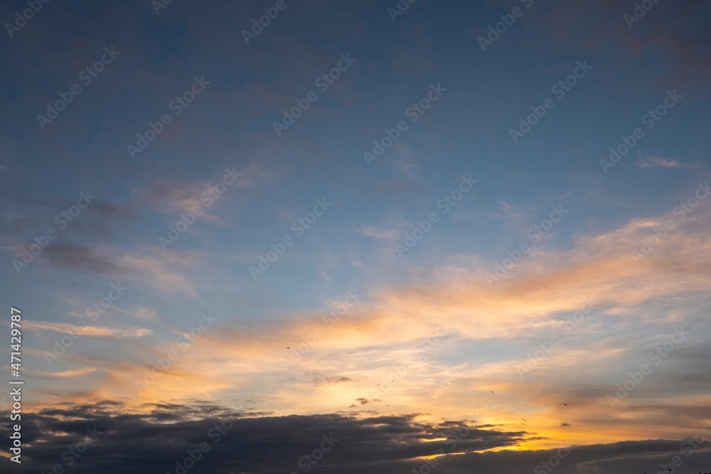 Stunning sunset cloudy sky. Low sun illuminates clouds in warm color. Nature background.