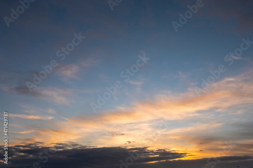 Stunning sunset cloudy sky. Low sun illuminates clouds in warm color. Nature background. © mark_gusev