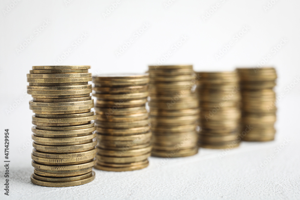 Many golden coins stacked on white table Many golden coins stacked on white table