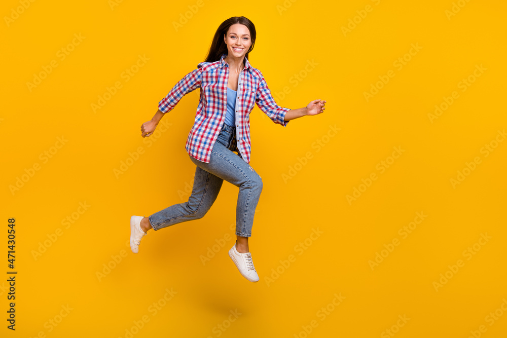 Full length profile photo of cheerful sportive lady jump run shopping wear plaid shirt isolated yellow color background
