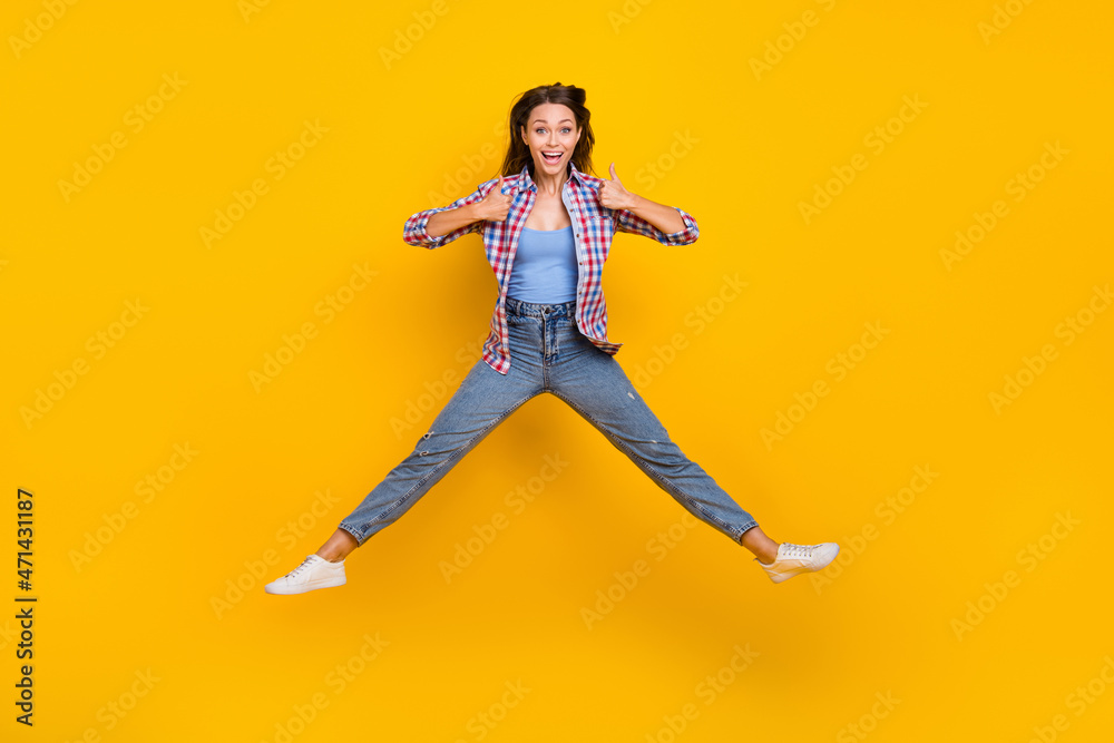 Full length photo of reliable lady jump raise thumbs up positive feedback wear plaid shirt isolated yellow color background