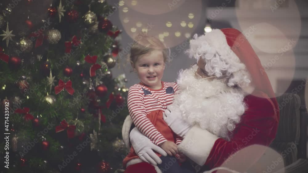 Little girl sitting on Santa Claus lap in decorated living room. Real time Little girl sitting on Santa Claus lap in decorated living room. Real time