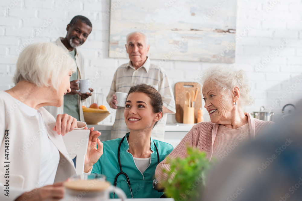 Young nurse spending time with smiling interracial patients in nursing home Young nurse spending time with smiling interracial patients in nursing home