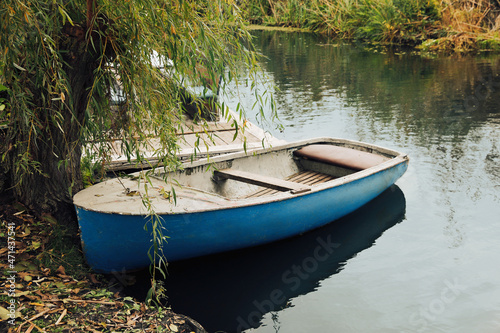Fototapeta Naklejka Na Ścianę i Meble -  Light blue wooden boat on lake near pier