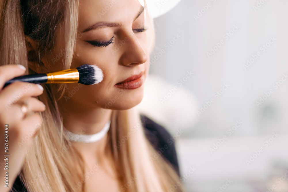 close-up. Woman applying makeup on cheekbones with makeup brush close-up. Woman applying makeup on cheekbones with makeup brush