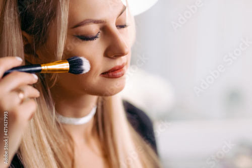 close-up. Woman applying makeup on cheekbones with makeup brush