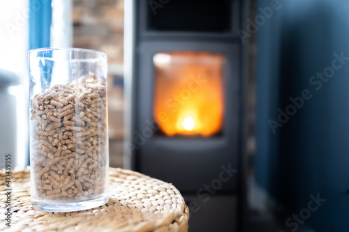 Fototapeta a pot of pellets to heat the fireplace with a wood stove in the background - hor