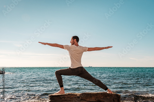 Attractive young man practicing yoga meditation and breath work outdoors by the sea 