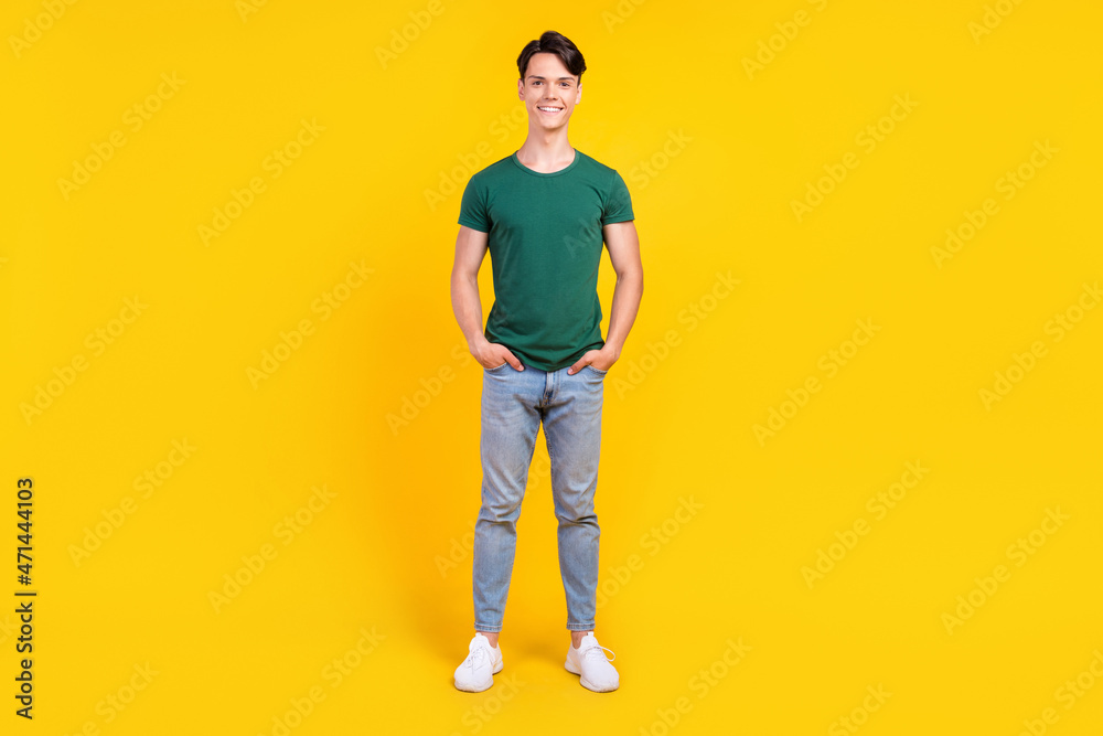 Fototapeta premium Full length photo of cheerful happy positive man hold hands pockets denim jeans isolated on yellow color background