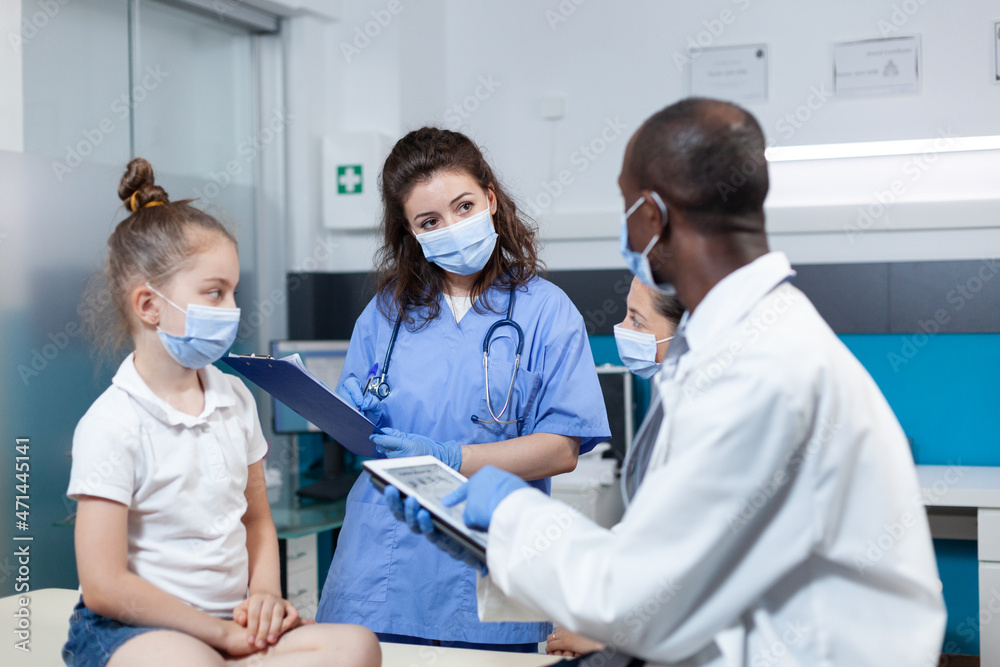 African american pediatrician doctor analyzing disease symptoms with nurse discussing healthcare treatment during clinical consultation in hospital office. Medical team with face mask against covid19 African american pediatrician doctor analyzing disease symptoms with nurse discussing healthcare treatment during clinical consultation in hospital office. Medical team with face mask against covid19