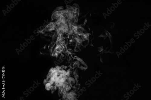Fragment of white hot curly steam smoke isolated on a black background, close-up. Abstract background, design element