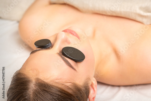 Massage with stones on the eyes of young woman getting a treatment in a beauty spa