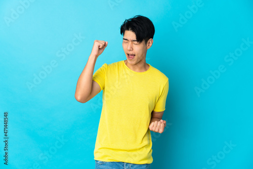 Young Chinese man isolated on blue background celebrating a victory