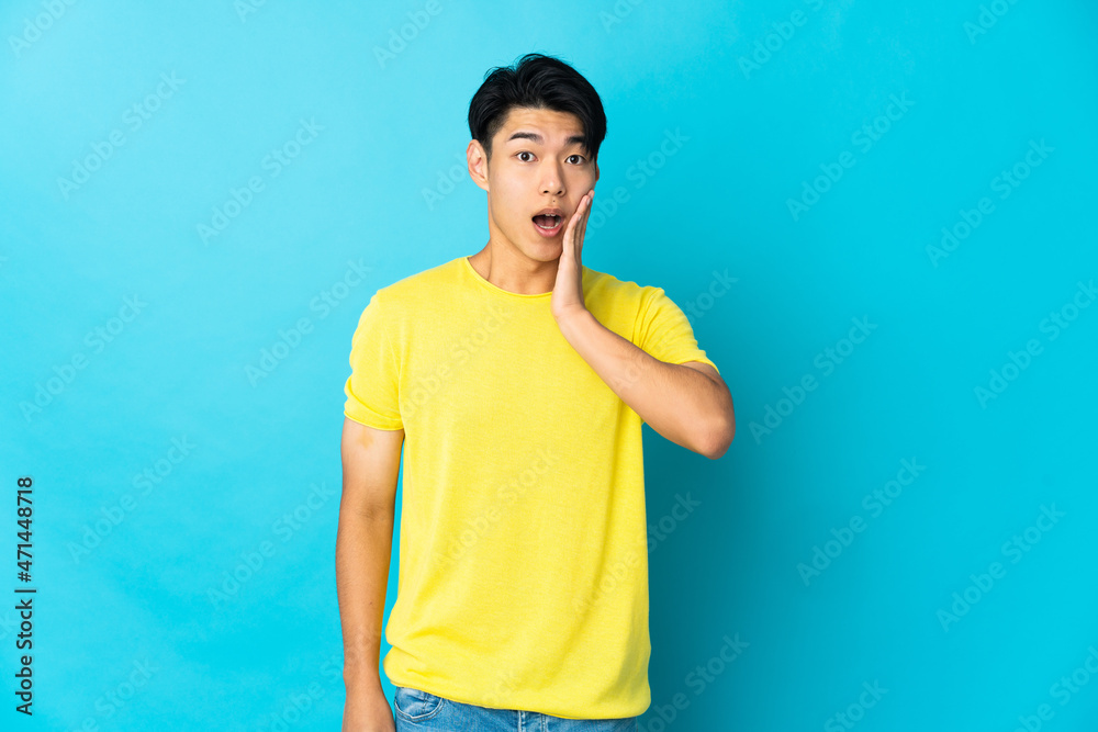 Young Chinese man isolated on blue background with surprise and shocked facial expression Young Chinese man isolated on blue background with surprise and shocked facial expression