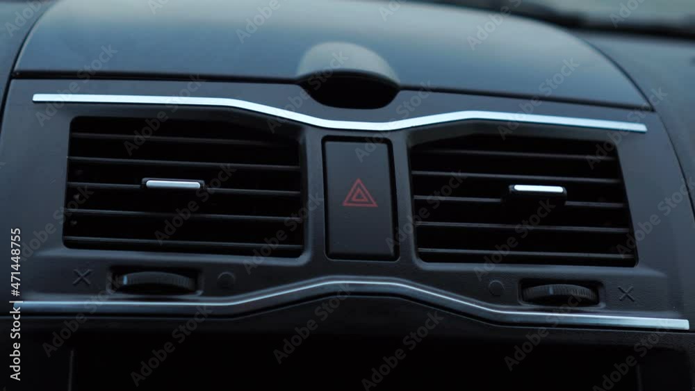 Woman pressing her finger on the car emergency lighting button on the dashboard. Woman pressing her finger on the car emergency lighting button on the dashboard.