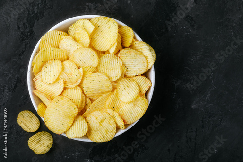 Potato chips. Crispy potato chips in bowl on a dark stone concrete background