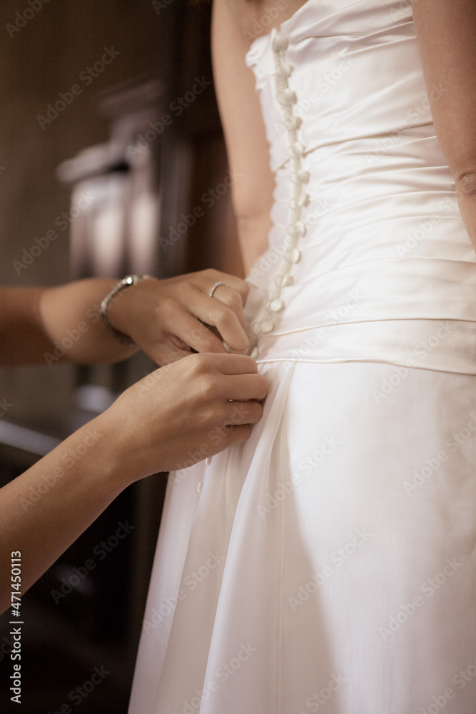 Close up bride assistant hands prepare back of white brides wedding dress low angle view background