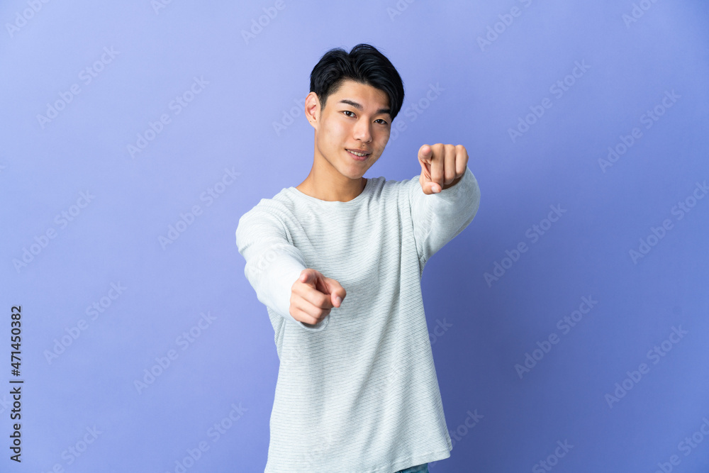 Naklejka premium Young Chinese man isolated on purple background pointing front with happy expression