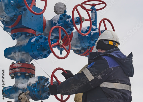 A gas company worker opens and closes high pressure valves on a gas tree photo