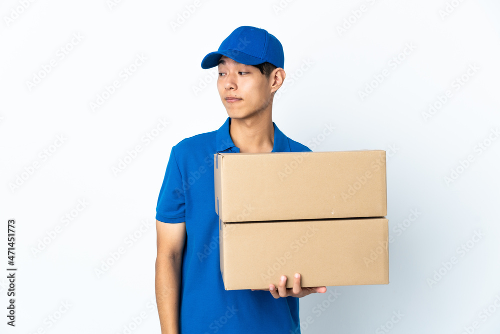 Delivery Chinese man isolated on white background making doubts gesture looking side Delivery Chinese man isolated on white background making doubts gesture looking side