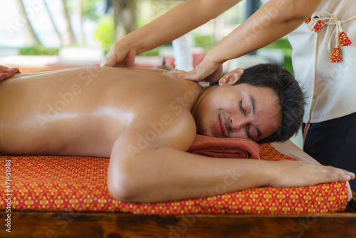 Asian man in beach spa salon getting oil massage near beach and looking happy in Thailand. Spa, resort, beauty and health concept.