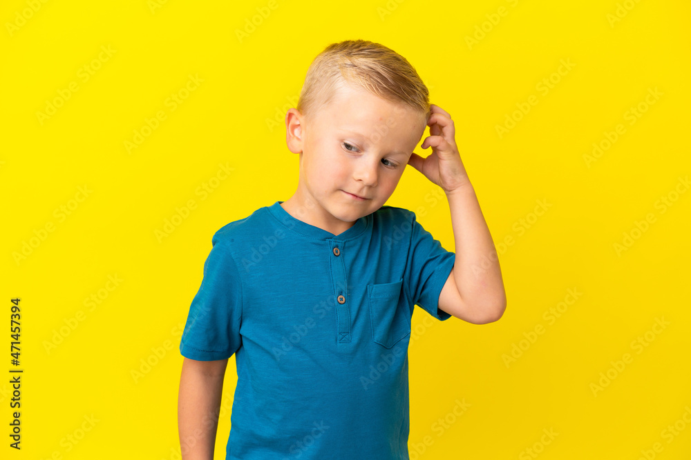 Little Russian boy isolated on yellow background having doubts Little Russian boy isolated on yellow background having doubts