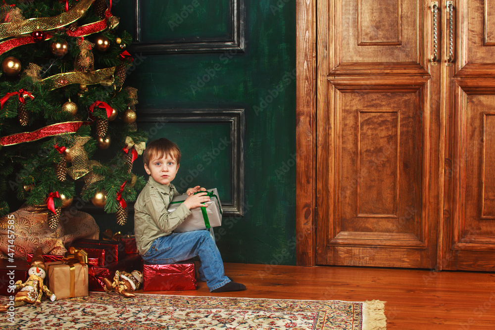 child boy sitting under the Christmas tree with gift box