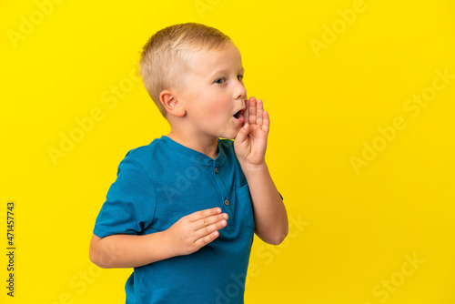 Little Russian boy isolated on yellow background shouting with mouth wide open to the side