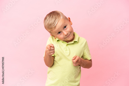 Little Russian boy isolated on pink background points finger at you with a confident expression