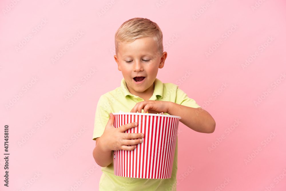 Little Russian boy eating popcorns in a big bowl over isolated background Little Russian boy eating popcorns in a big bowl over isolated background